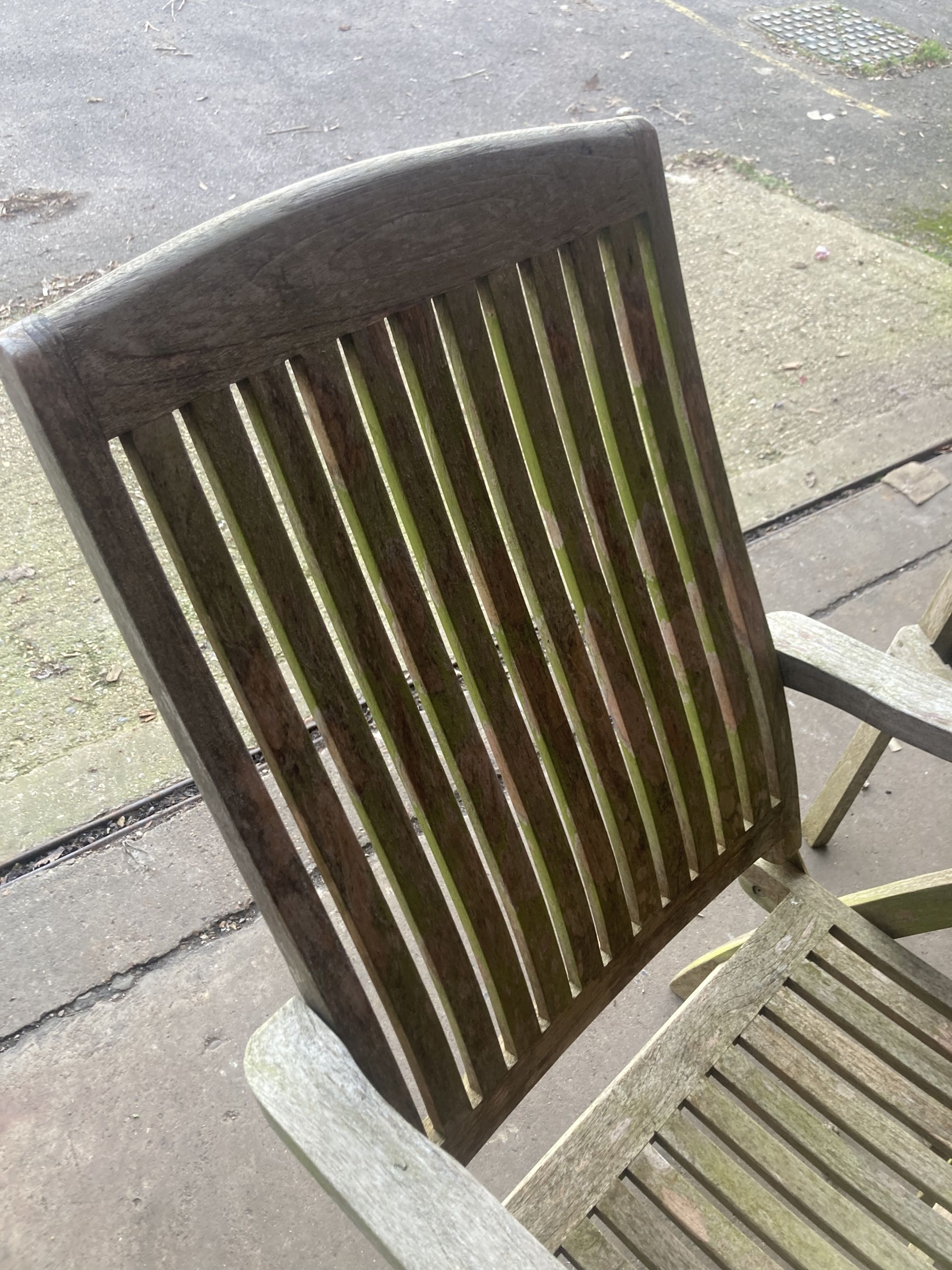 A weathered teak folding garden armchair, together with a teak garden elbow chair